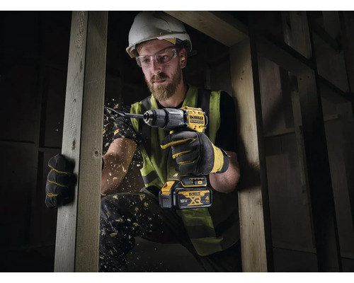 Remeselník vŕta drevenú dosku akumulátorovou vŕtačkou