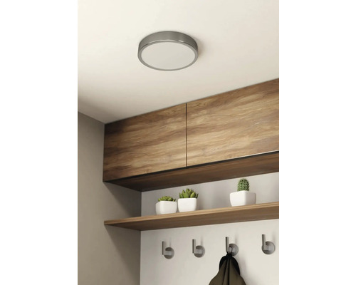 Stropné svietidlo v svetlej miestnosti s drevenými skriňami, policou a vešiakom.