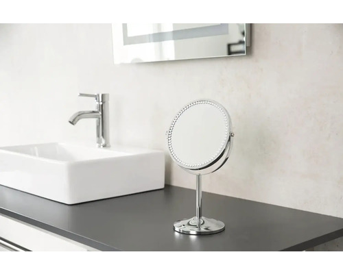 Na umývadle stojí zrkadlo, umývadlo a kohútik.