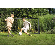 Dvaja chlapci hrajú futbal pred futbalovou bránkou v záhrade.