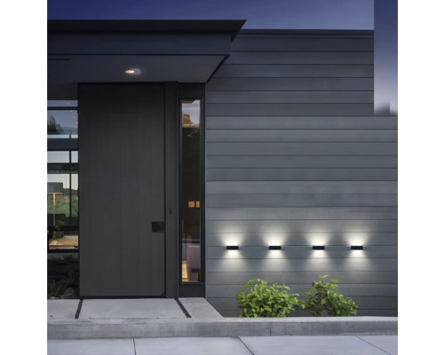 Moderná fasáda domu so vstupnými dverami a tromi osvetlenými nástennými svietidlami