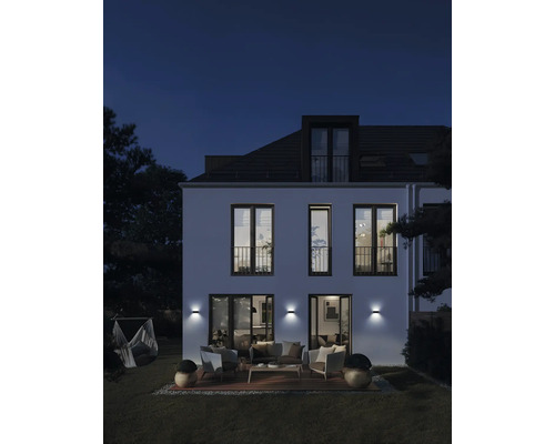 Fasáda domu s vonkajším osvetlením, terasou a záhradným nábytkom v noci