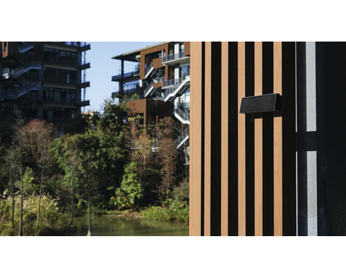 Pohľad na modernú budovu s drevenou fasádou a poštovou schránkou v zelenom prostredí