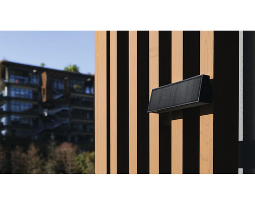 Čierne vonkajšie nástenné svietidlo na drevenej fasáde.