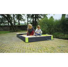 Dve deti sa hrajú na záhrade v pieskovisku s hračkovou kuchynkou.