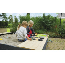 Dve deti sa hrajú na pieskovisku s hracou kuchyňou v záhrade.