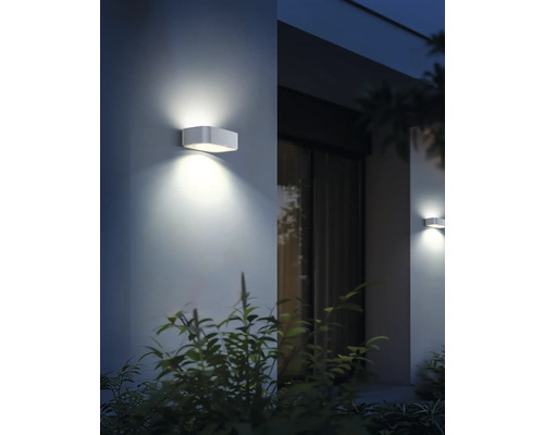 Dve obdĺžnikové kovové nástenné svietidlá, ktoré vyžarujú teplé svetlo a vytvárajú príjemnú atmosféru.