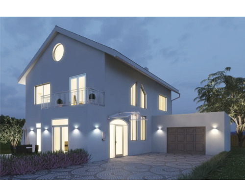 Pohľad na dom s osvetlením, garážou a dláždenou príjazdovou cestou v noci