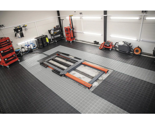 Dielňa so zdvihákom, vozíkom na náradie a čistiacimi zariadeniami na dlažbovej podlahe