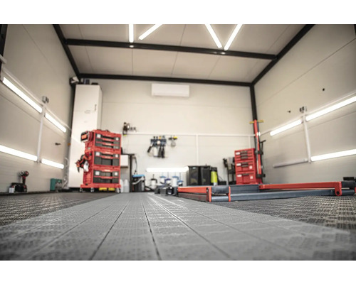 Svetlá dielňa s vozíkmi na náradie, ponkom a podlahovými ochrannými rohožami