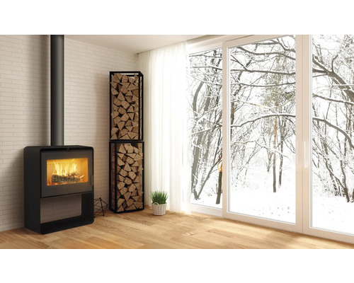 Obývacia izba s krbovými kachľami, regálom na drevo a výhľadom na zasnežené stromy