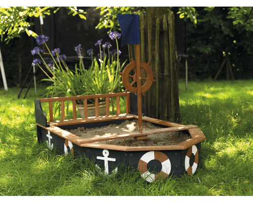 Pieskovisko v tvare lode s kormidlovým kolesom, vlajkou a námornými dekoráciami v záhrade