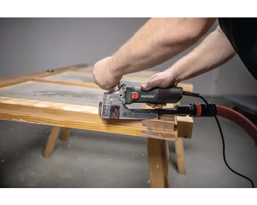 Muž pracuje s drážkovacou frézkou Metabo na drevenom ráme.