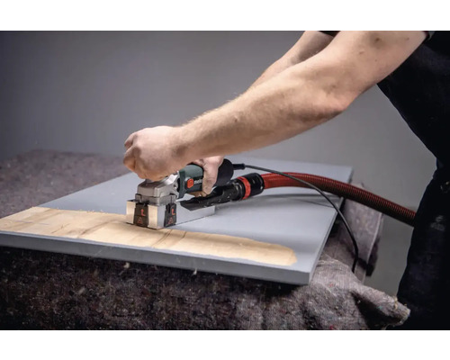 Osoba používa drážkovaciu frézu na obrobok.