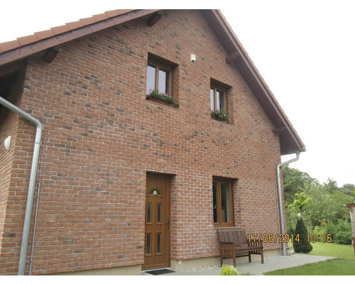 Pohľad na dom s tehlovým murivom, oknami a drevenými dverami