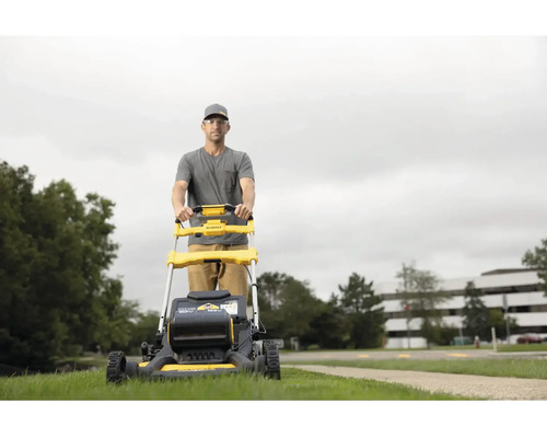 Muž obsluhuje žltú kosačku na trávu značky DeWalt vonku.