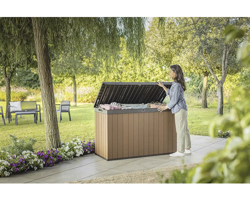 Záhradná scéna so ženou, ktorá sa pozerá na otvorený úložný box v záhrade