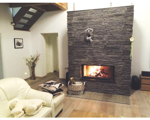 Obývacia izba s kamenným krbom, kreslom a dreveným schodiskom