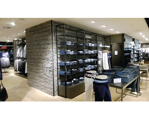 Interiér obchodu s oblečením s regálmi a stolmi s džínsami a nohavicami