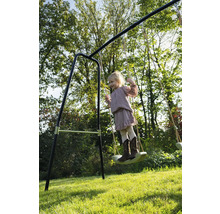 Dievča sa húpa na hojdačke v záhrade.