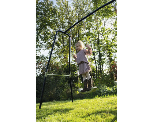 Dievča sa húpa na hojdačke v záhrade.