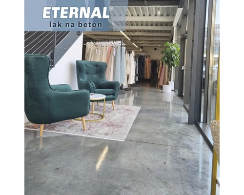 Interiér s ošetrenou betónovou podlahou, dve kreslá a vešiak na šaty v pozadí.