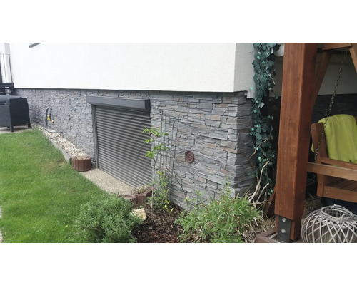 Exteriér domu s kamennou fasádou, okennými roletami a záhradou