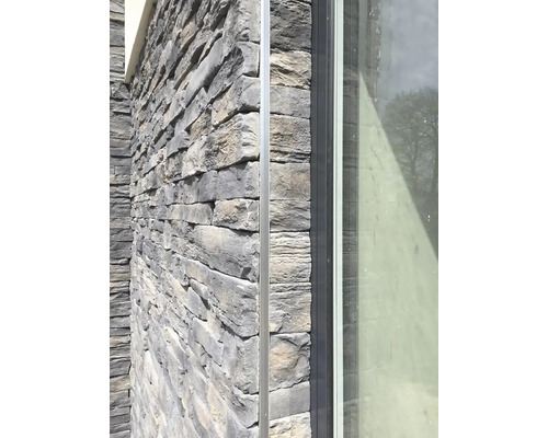 Detail fasády domu s kamenným obkladom a oknom