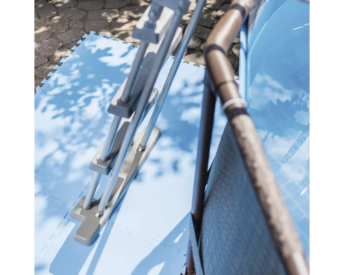 Bazénový rebrík a bazén na modrých bazénových rohožiach