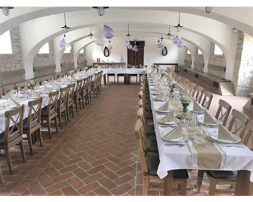 Vyzdobená sála s dlhými stolmi na oslavu.