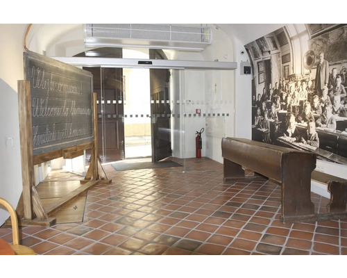 Vstupný priestor s bridlicovou tabuľou, školskou lavicou a historickou fotografiou školskej triedy