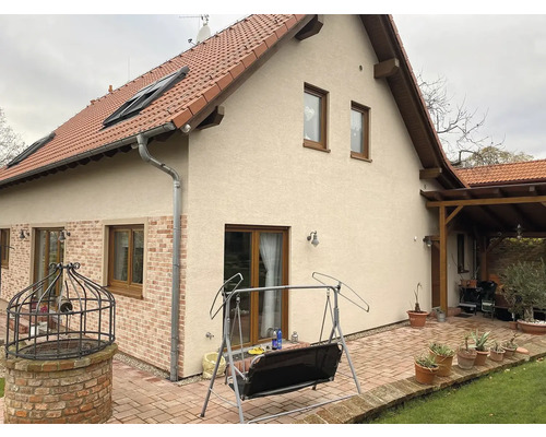 Vonkajší pohľad na dom s tehlovou strechou, oknami a dláždenou terasou