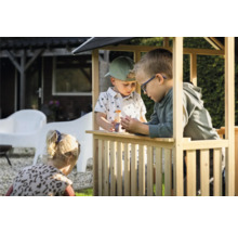 Tri deti sa hrajú v drevenom hracom domčeku v záhrade.