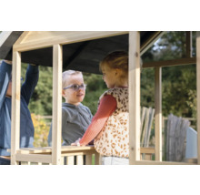 Dve deti sa hrajú v neošetrenom drevenom domčeku na hranie v záhrade.