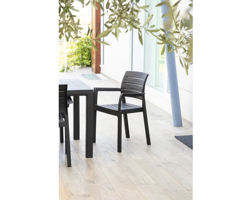 Plastová záhradná stolička s opierkami na ruky vedľa záhradného stola