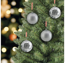 Detailný záber štyroch strieborných vianočných gúľ visiacich na vianočnom stromčeku