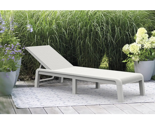 Záhradná scéna so svetlým záhradným lehátkom na koberci, obklopená rastlinami