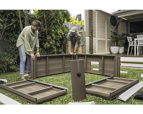 Dvaja ľudia montujú záhradný domček na trávniku.