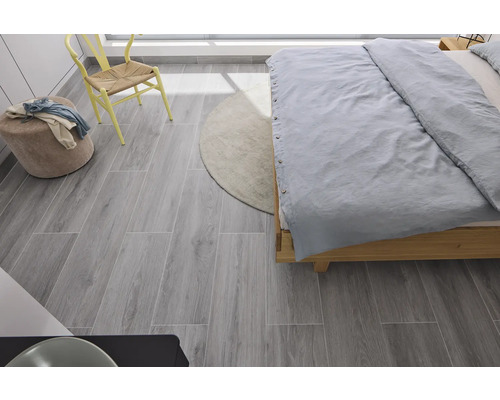 Spálňa s posteľou, stoličkou, taburetkou, kobercom a sivou dlažbou s dreveným dekorom