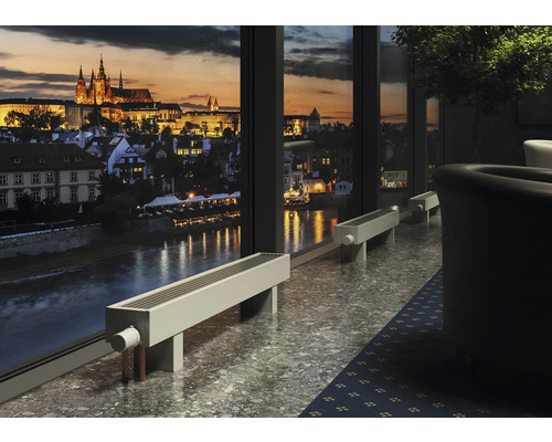 Scéna miestnosti s radiátormi pred oknom s výhľadom na mesto v noci.