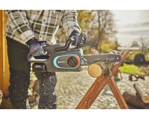 Osoba reže drevo pomocou akumulátorovej reťazovej píly Gardena na drevenej koze