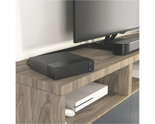 Rozbočovač napájania Legrand na drevenej polici pod televízorom.