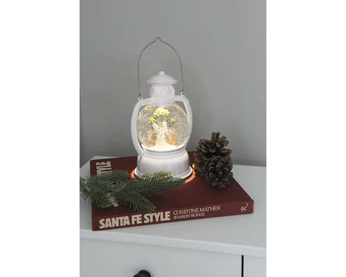 Dekoratívna lampa so snehovou guľou, anjelom a vianočným stromčekom na nočnom stolíku