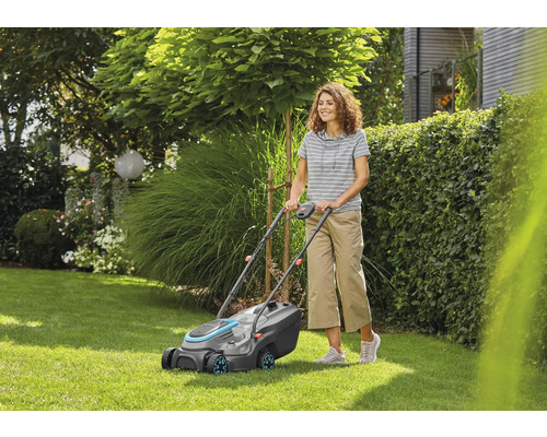 Žena obsluhuje kosačku na trávu v záhrade