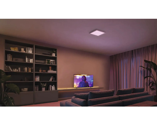 Obývacia izba s knižnicou, televízorom, pohovkou a štvorcovým stropným svietidlom