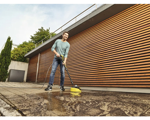 Muž čistí dlažobné kocky pomocou plošného čističa a tlakovej umývačky.