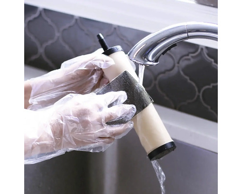 Čistenie vložky vodného filtra pod vodovodným kohútikom pomocou drôtenky