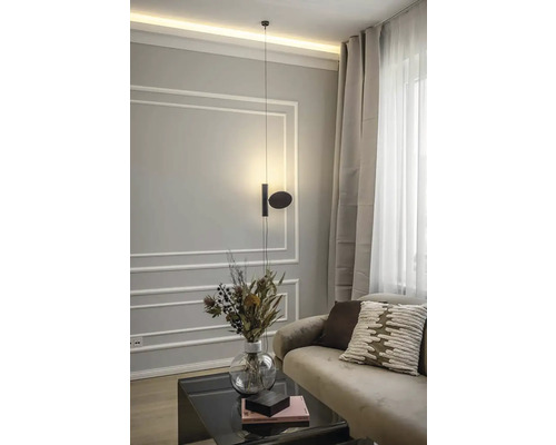 Moderná obývacia izba s visiacou lampou, pohovkou, vankúšmi, konferenčným stolíkom a vázou s kvetinami.