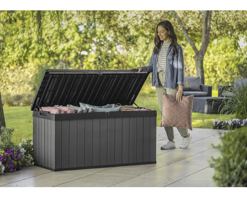 Otvorený plastový záhradný box s vankúšmi a ženou v záhrade