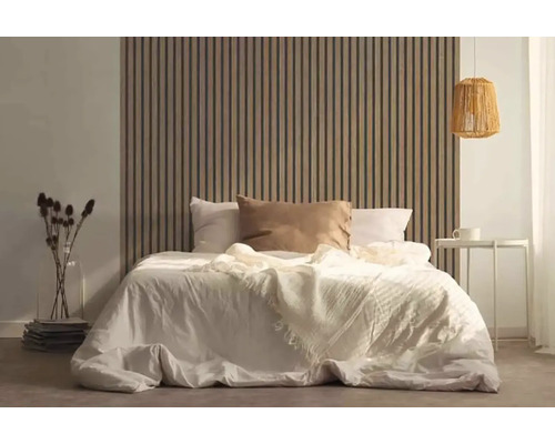 Spálňa s posteľou pred dreveným lamelovým obkladom stien, nočným stolíkom a lampou